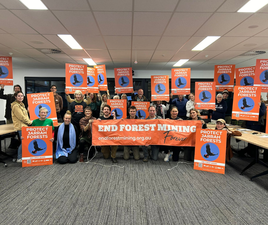 Around 20 people holding signs and banners at a workshop