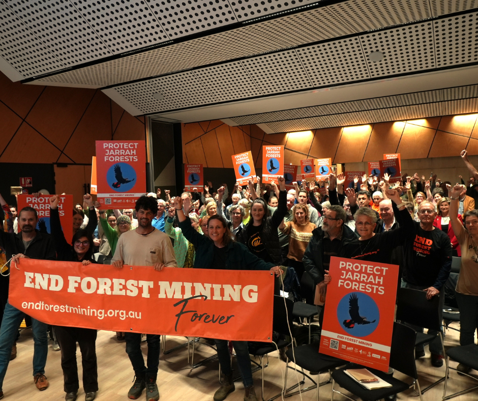A full town hall with people holding signs and banners