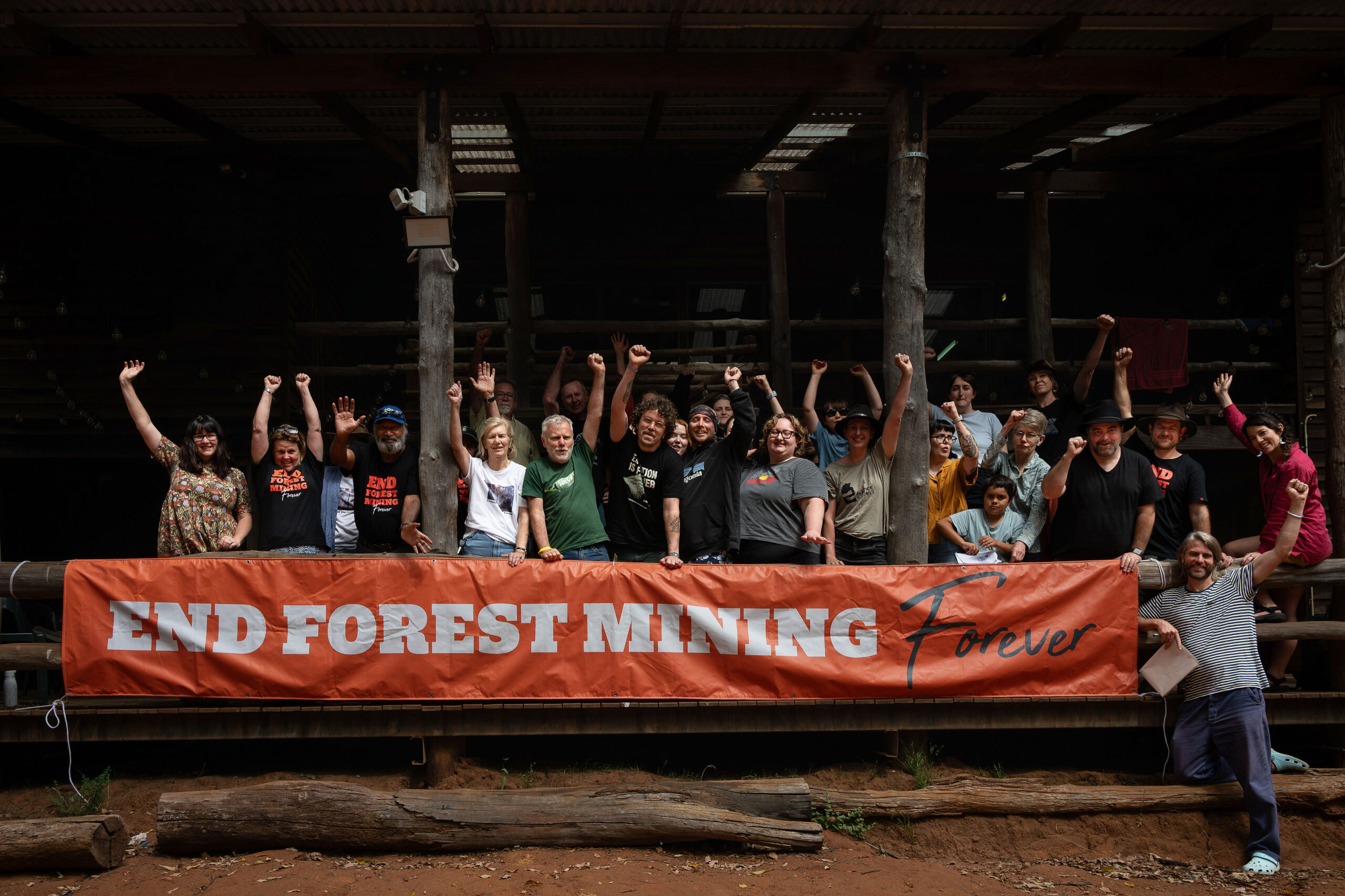 A crowd of people behind a sign that reads "End Forest Mining"